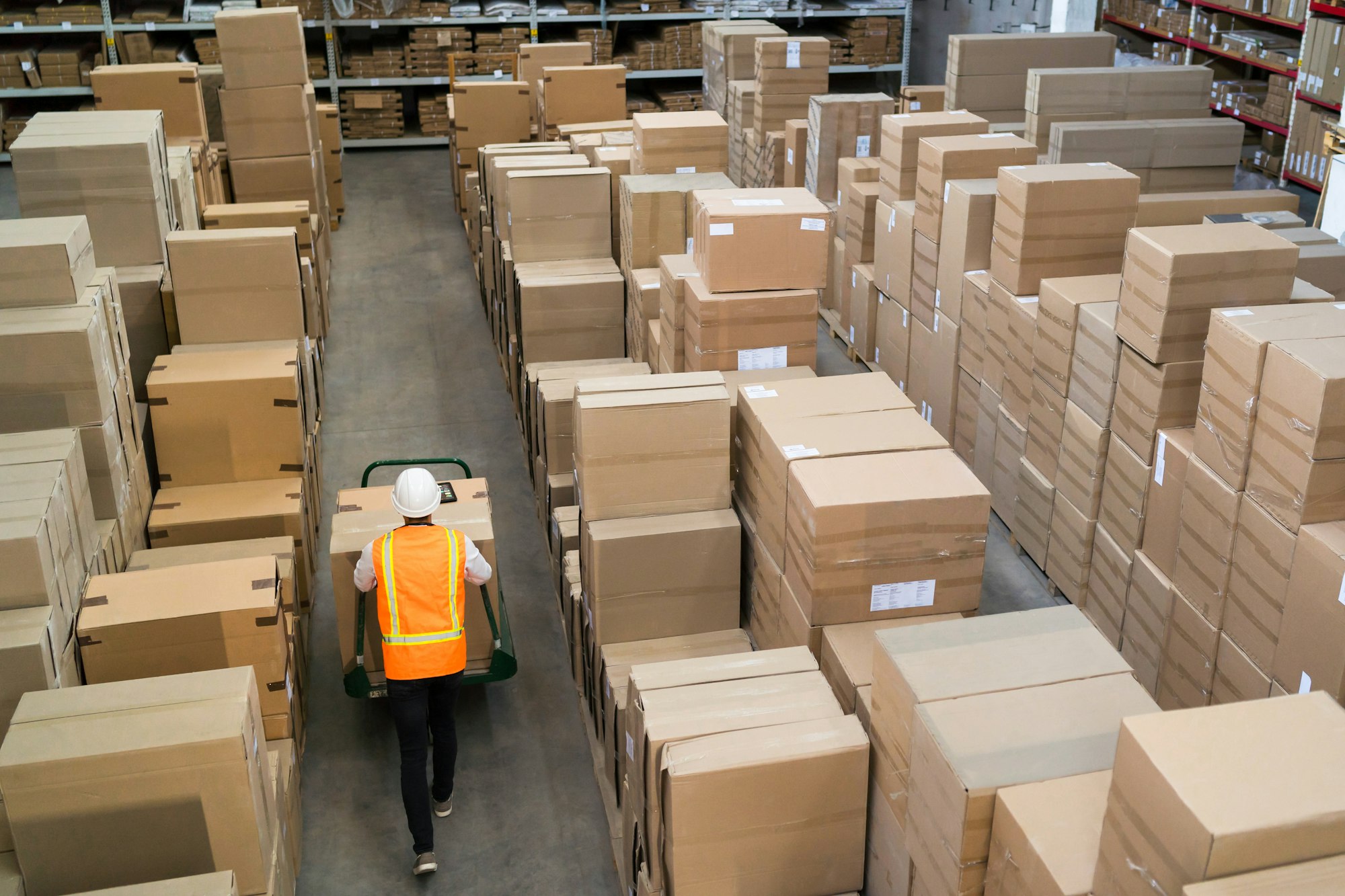 Logistic warehouse worker delivering boxes on a trolley